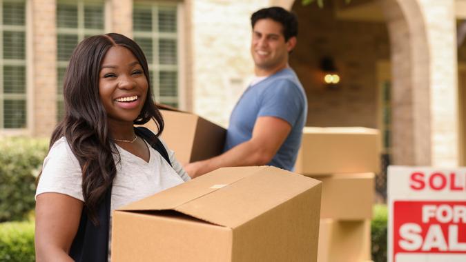Mixed race family of African and Latin descent moving boxes into a new home.
