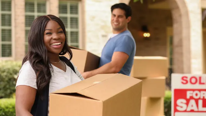 Mixed race family of African and Latin descent moving boxes into a new home.