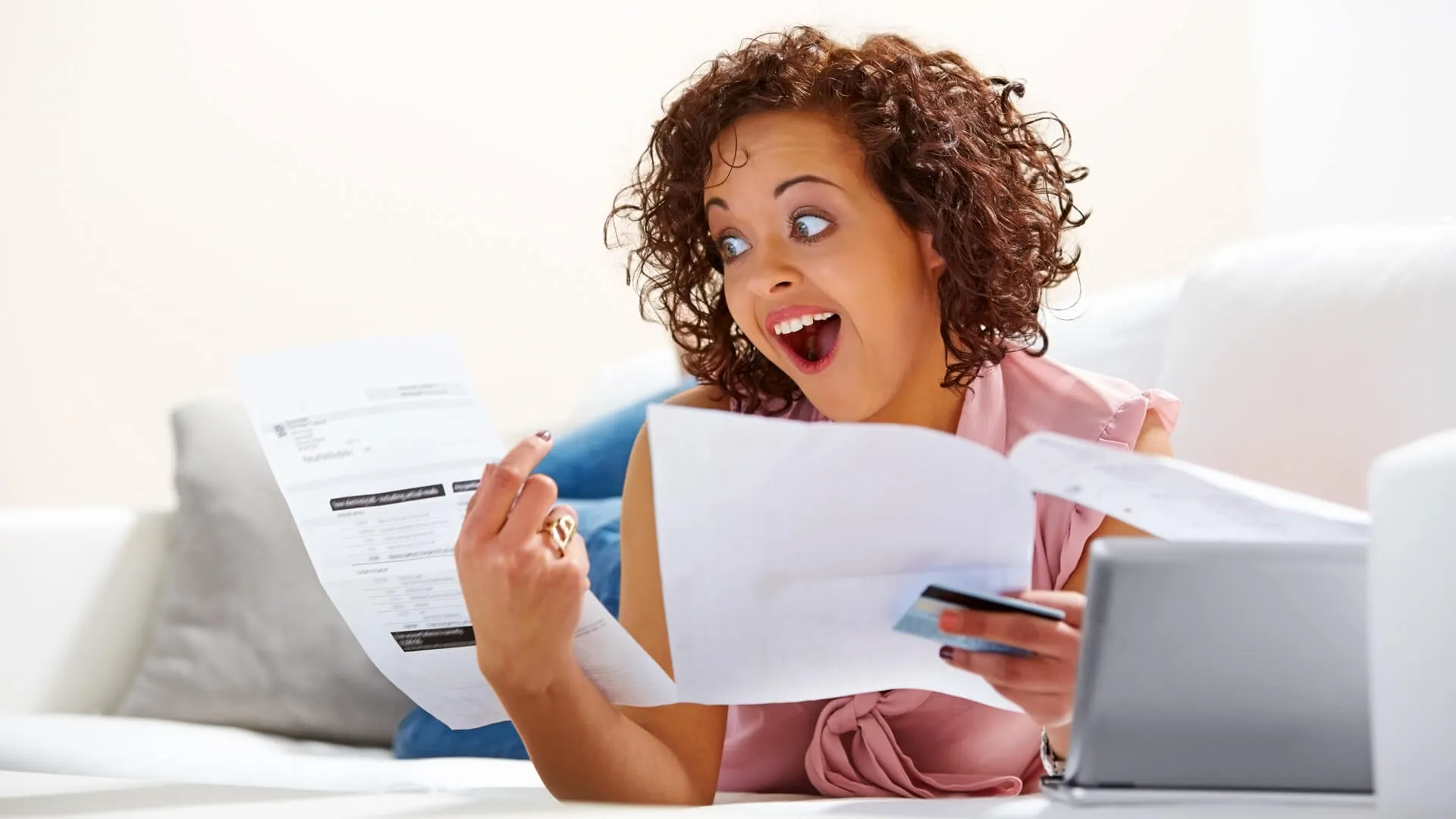 Image of young lady looking excited after looking at her credit card bill.