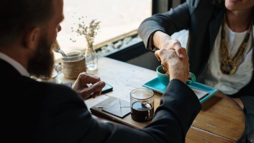 Business agreement handshake at coffee shop.