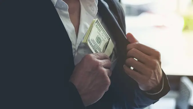 Business man hiding money in pocket.