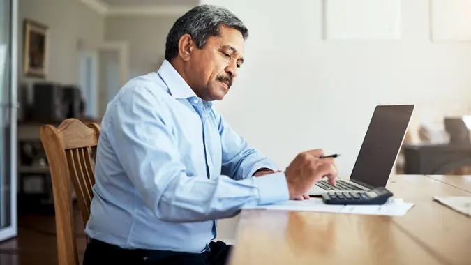Cropped shot of a senior man using a laptop to do the household finances.