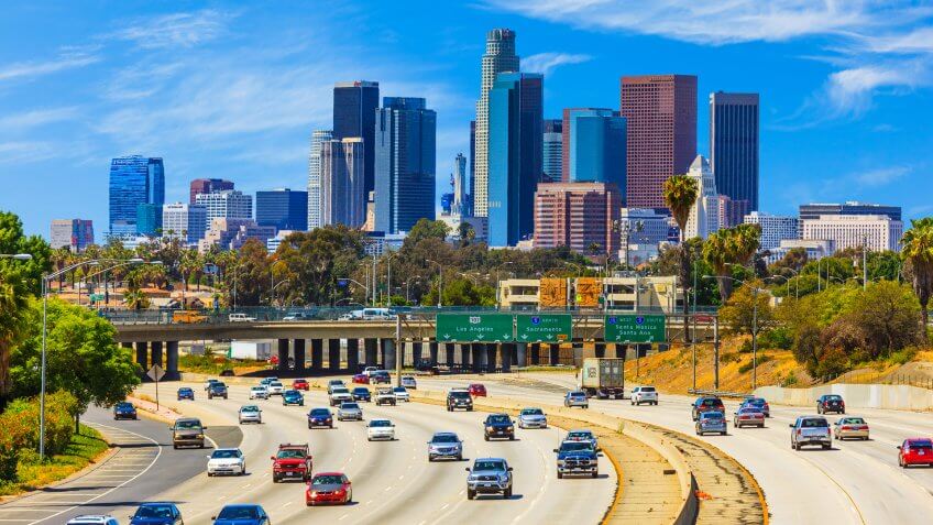 Heavy traffic on freeway leading back to skyscrapers of Los Angele skyline.