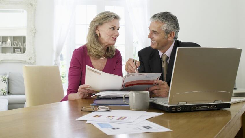 Mature woman sitting at table with financial advisor.