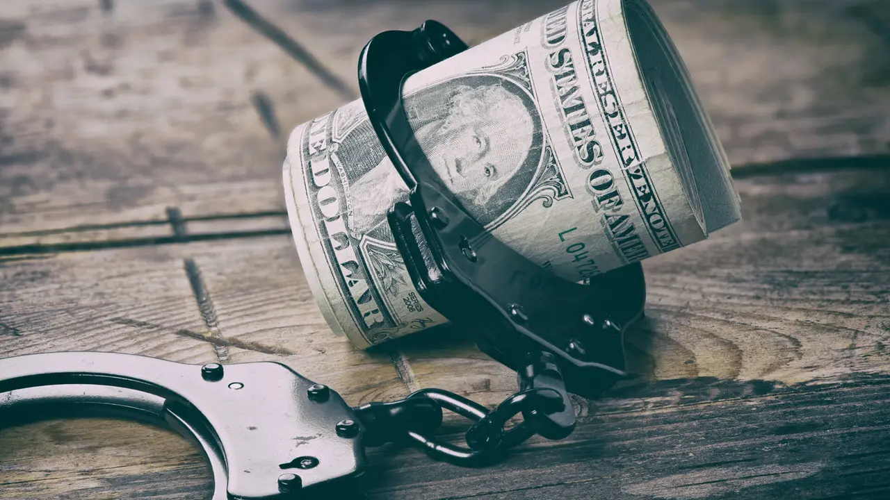 Handcuffs and money on wooden table.