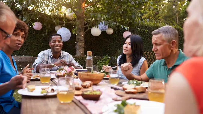 Group Of Mature Friends Enjoying Outdoor Meal In Backyard.