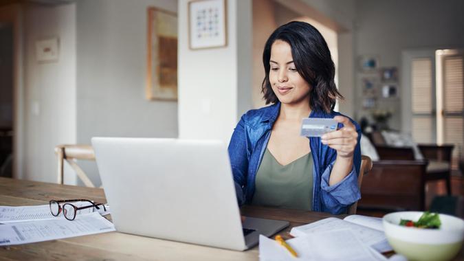 Shot of a young woman using a laptop and credit card while working from home.