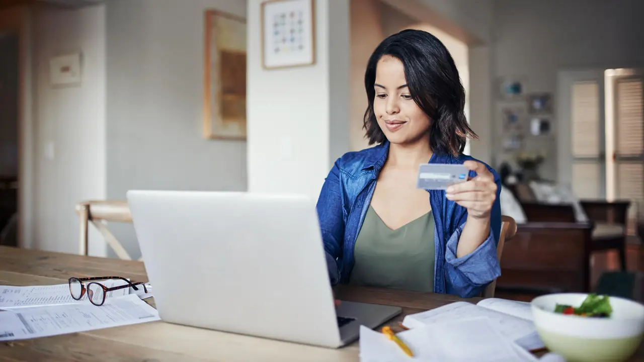 Shot of a young woman using a laptop and credit card while working from home.