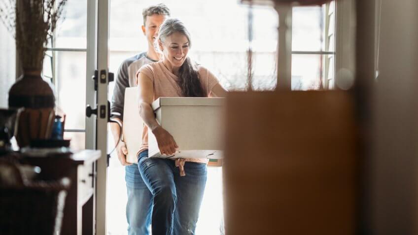 A couple in their 50's moves in to their new home, unpacking boxes and enjoying the time together.