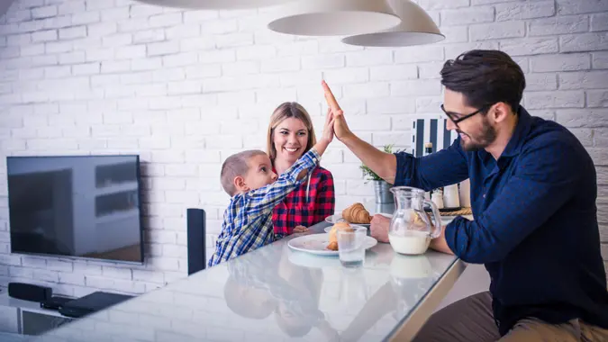 Giving high five to daddy while eating in the kitchen.