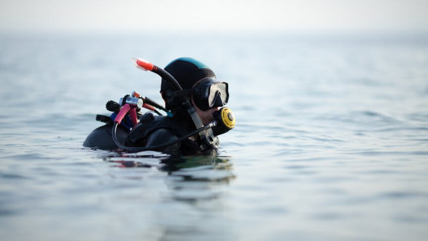 Woman scuba diver going underwater and setting her equipment.