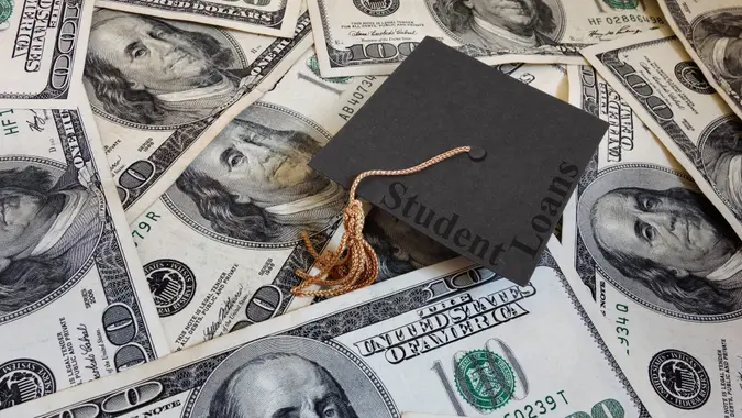 微型毕业帽和学生贷款文本,在各种各样的现金。