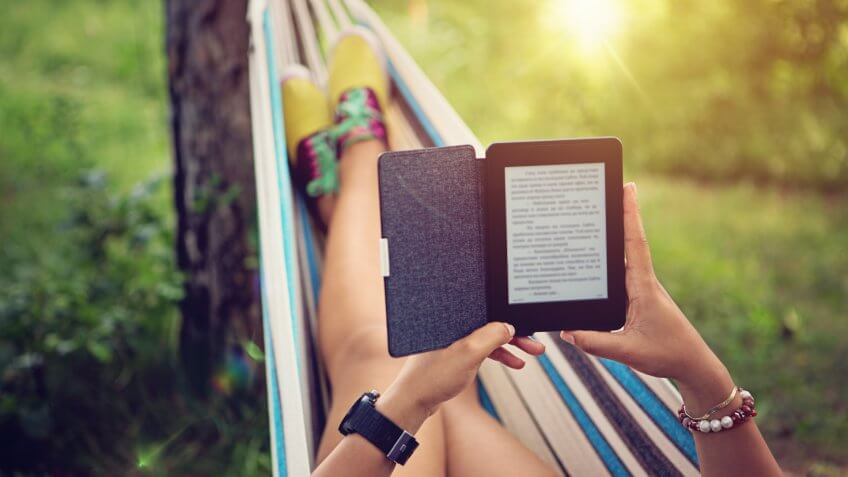 Beautiful girl is reading e-book in the hammock.