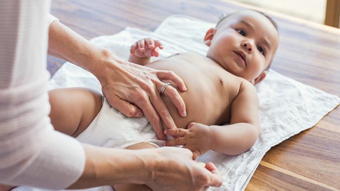 Mother hands changing baby nappy.