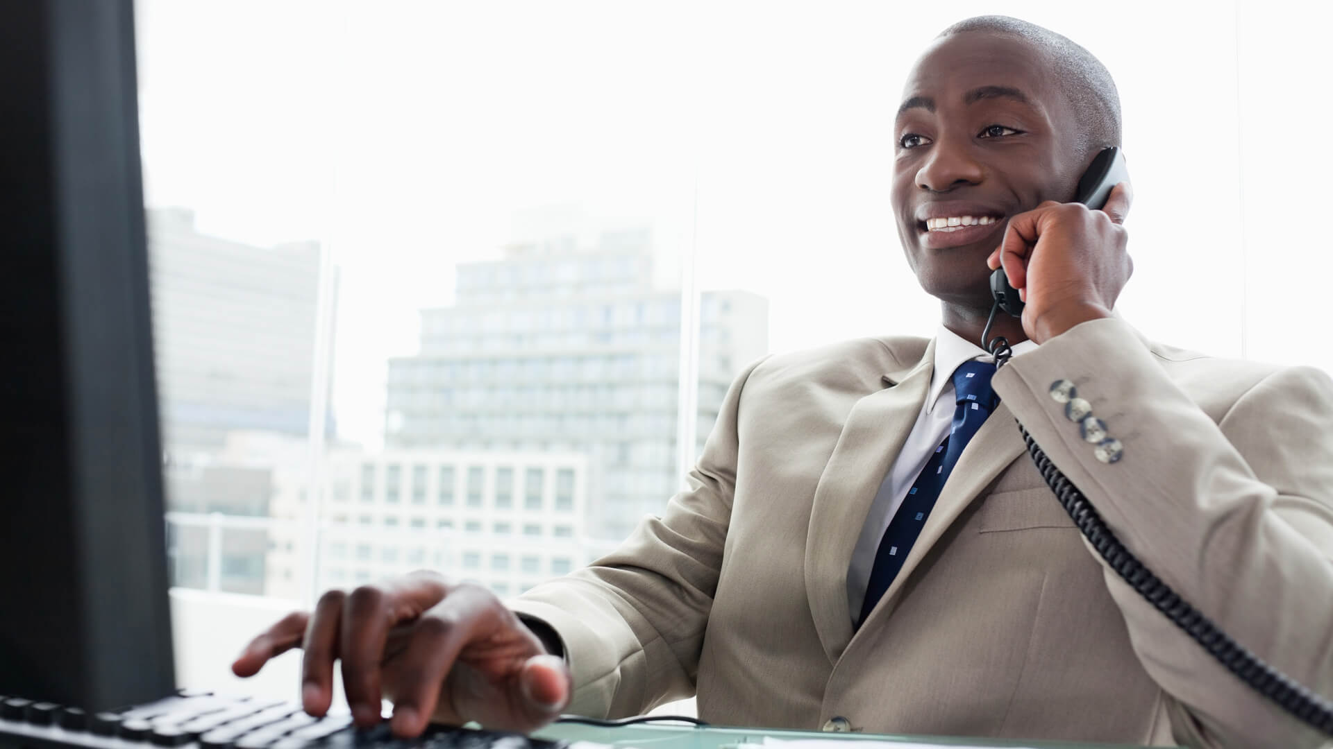 22 Industries That Pay Less (and More) Than They Did 10 Years Ag, Businessman on the phone while using a computer in his office