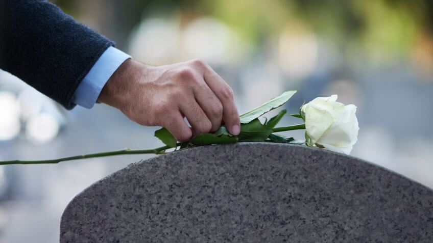placing a white rose on a grave