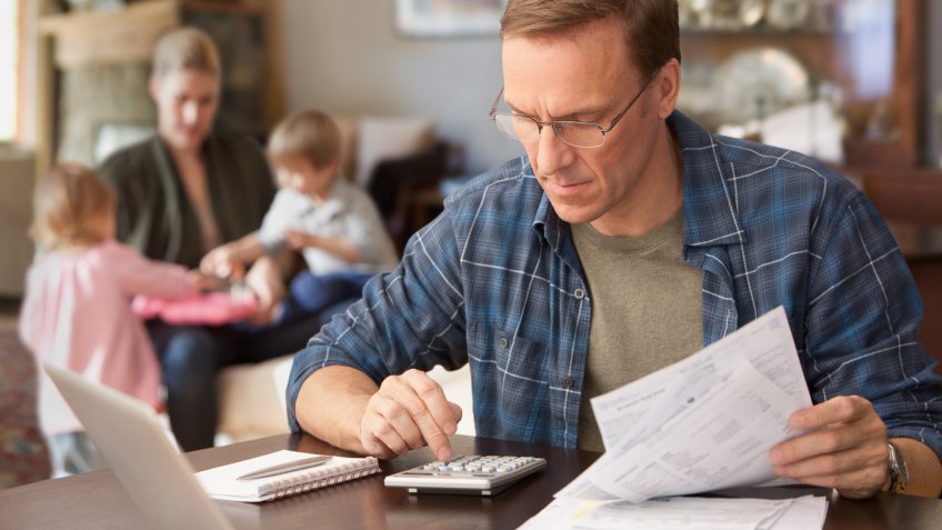 Father paying bills with family behind him.