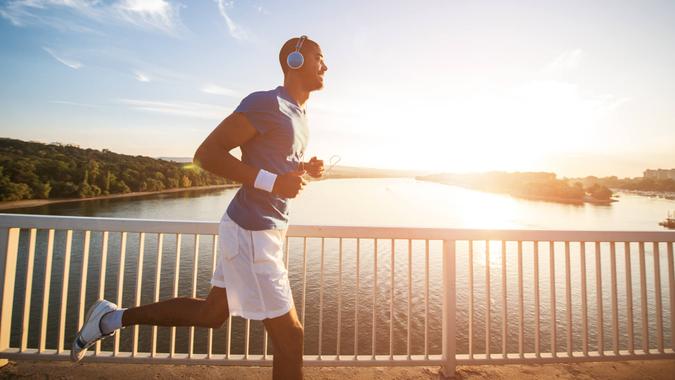 A young man running on the bridge along a river.