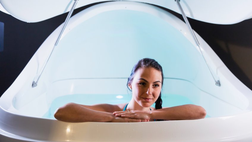 A relaxed young woman leaning on the edge of a sensory deprivation tank.