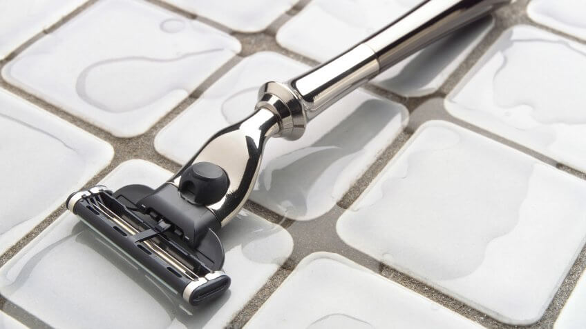 Elegant, modern razor on bathroom wet tile surface.