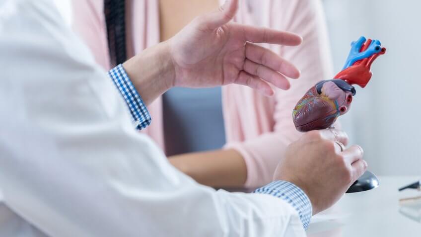 Male cardiologist gestures while discussing diagnosis with an unrecognizable female patient.