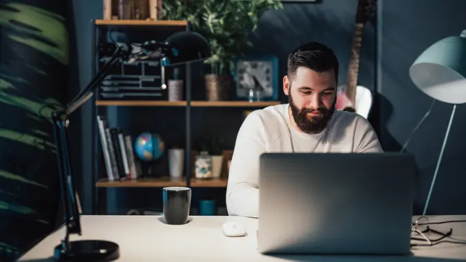 man working on laptop on his finances and emergency fund