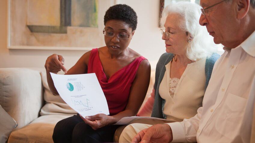 Mid adult woman showing financial paperwork to senior couple.