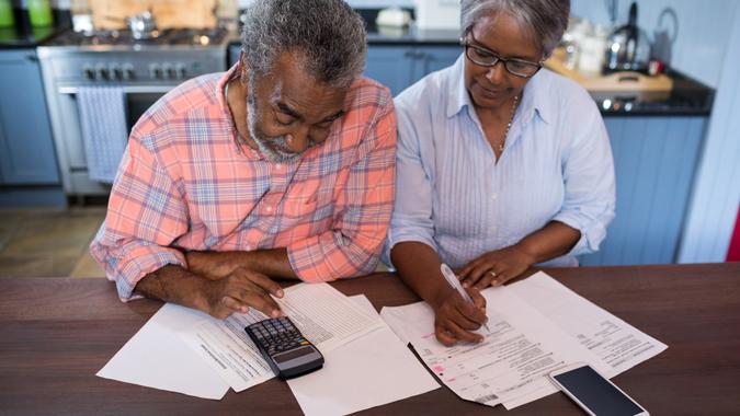 High angle view of couple using calculator in kitchen at home.