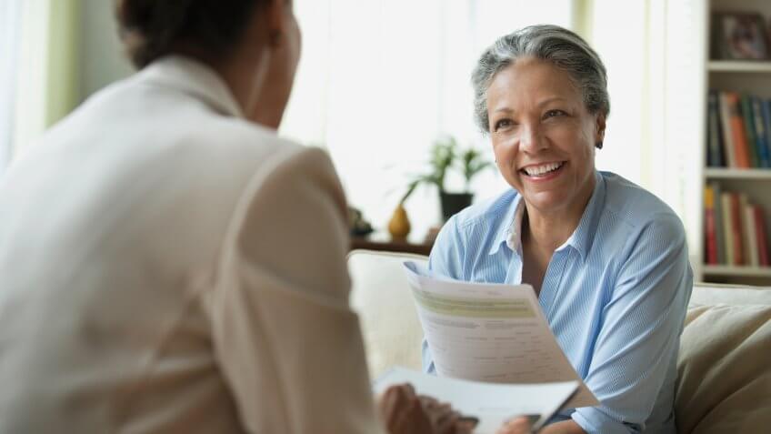 Hispanic saleswoman talking to client in living room.