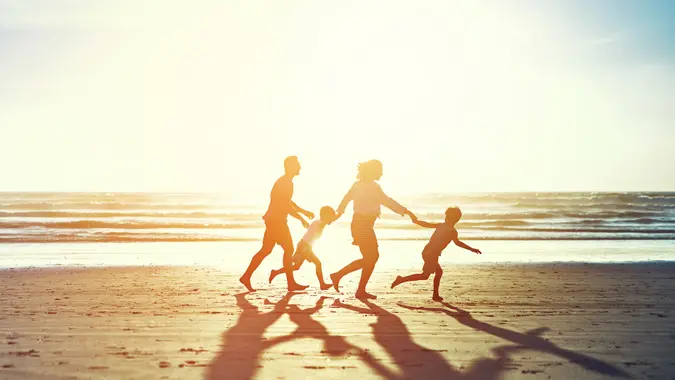 family of four enjoying a run on the beach