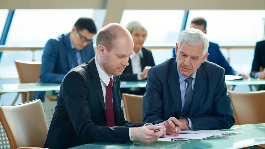 Two serious men looking at document.