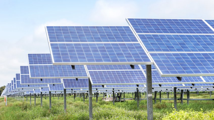 rows array of polycrystalline silicon solar cells or photovoltaics in solar power plant turn up skyward absorb the sunlight from the sun on blue sky background.