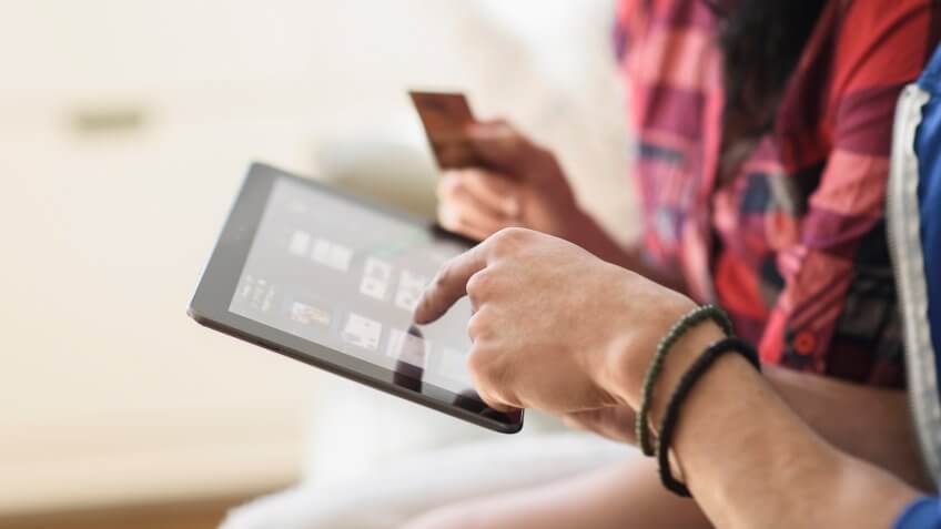 Close up of couple shopping online on digital tablet.