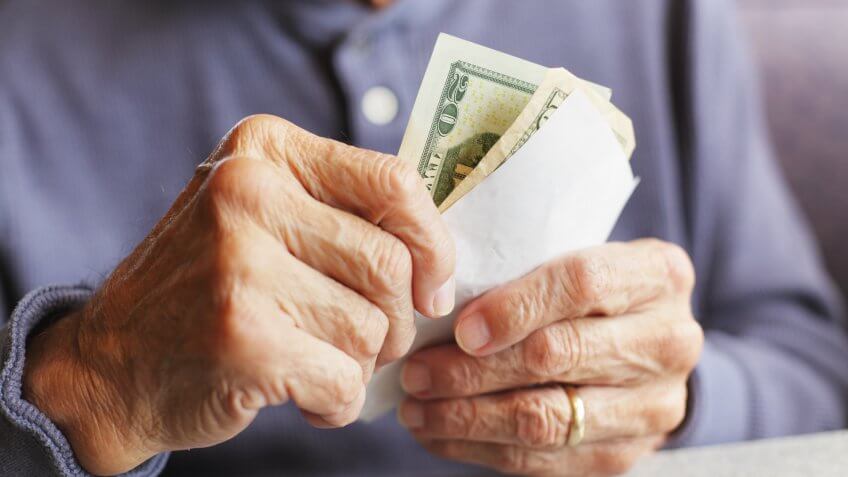 A senior man wearing a gold wedding ring is holding U.