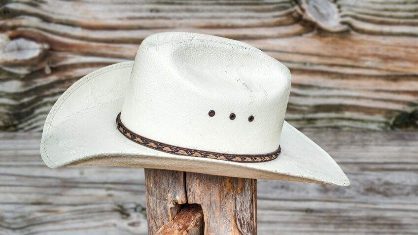 Straw cowboy hat against a weathered wood fence.