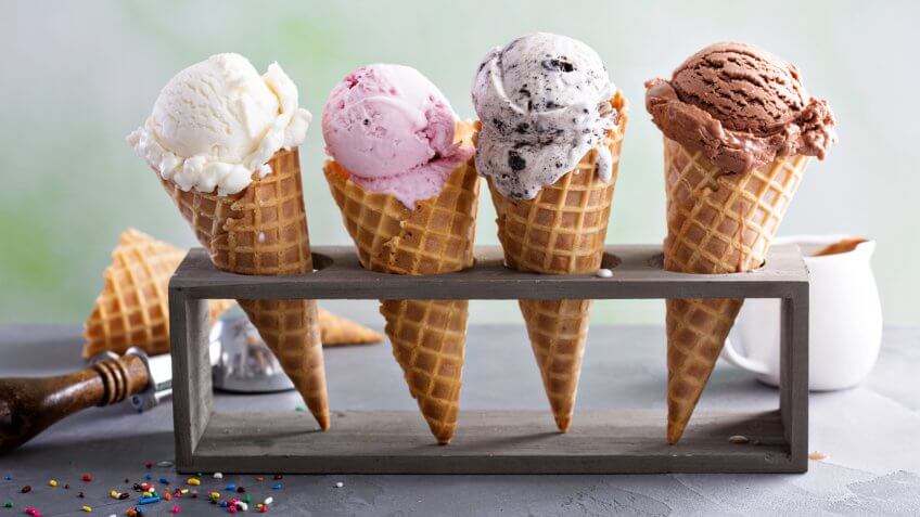 Variety of ice cream scoops in cones with chocolate, vanilla and strawberry.