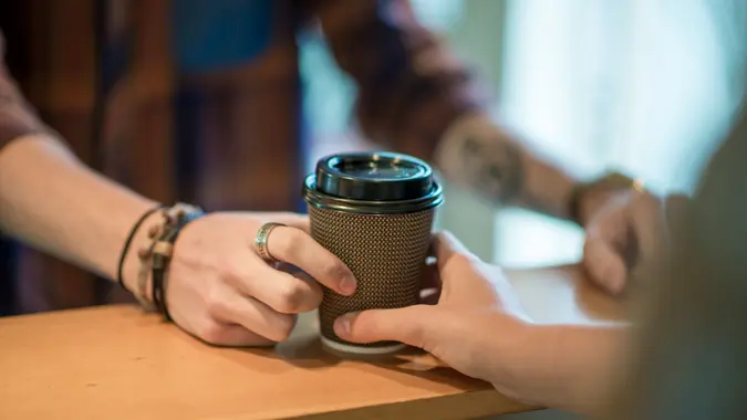 A man is buying a cup of coffee from a local cafe.