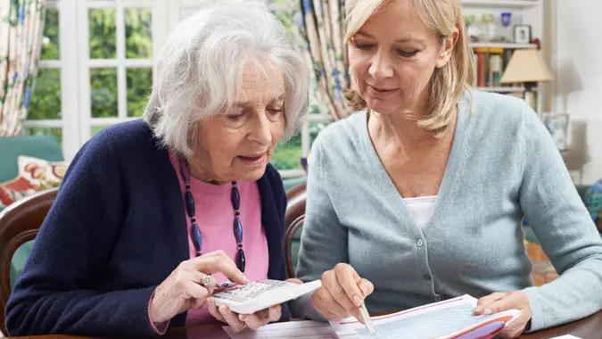 Mature Woman Helping Senior Neighbor With Home Finances.