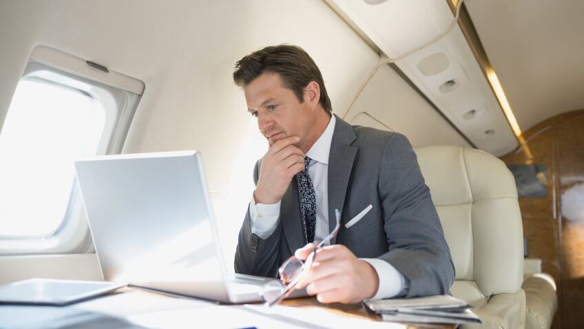 Businessman with laptop working on corporate jet.