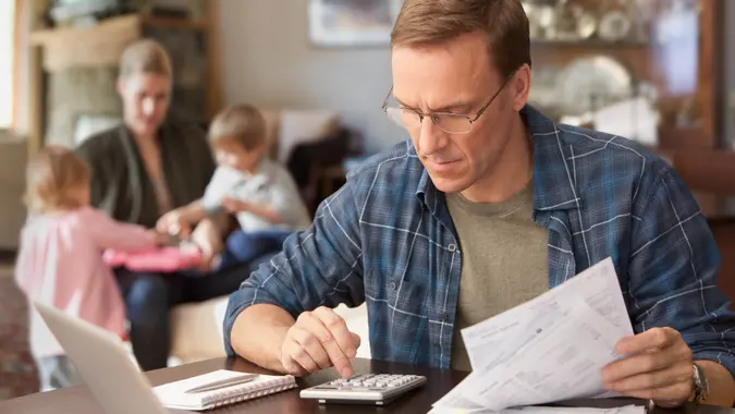 Father paying bills with family behind him.