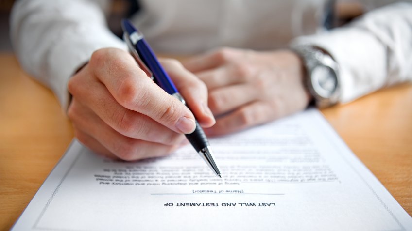 Female hands signing Last Will and Testament.