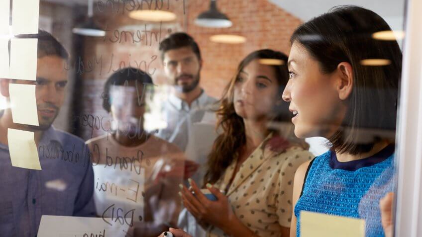 Businesswoman Writing Ideas On Glass Screen During Meeting.