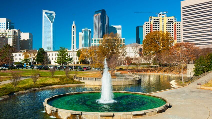 Downtown Charlotte skyscrapers in the background with a park (Marshall Park), fountain and waterway in the foreground.