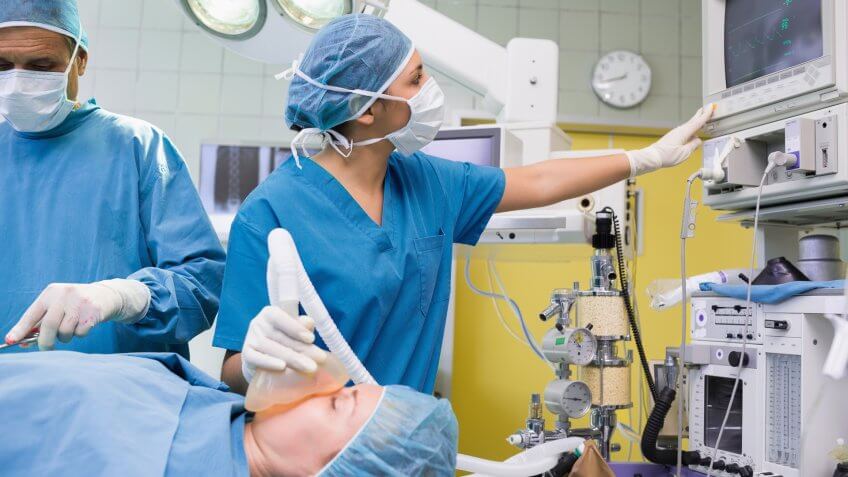 Anesthetist checking the ECG machine during an operation in a hospital.