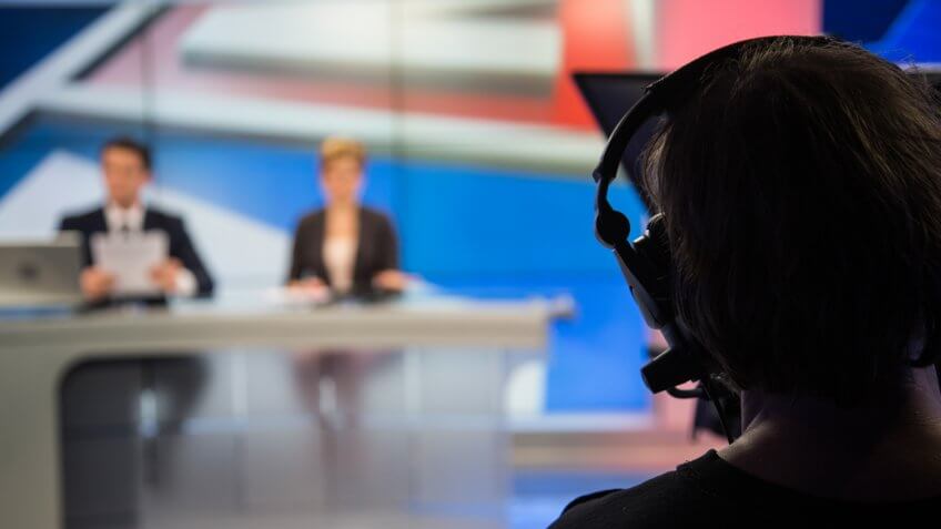 Cameraman filming news in television studio.