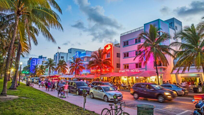 Miami, USA - August 23, 2014: people enjoy Palm trees and art deco hotels at Ocean Drive by night.