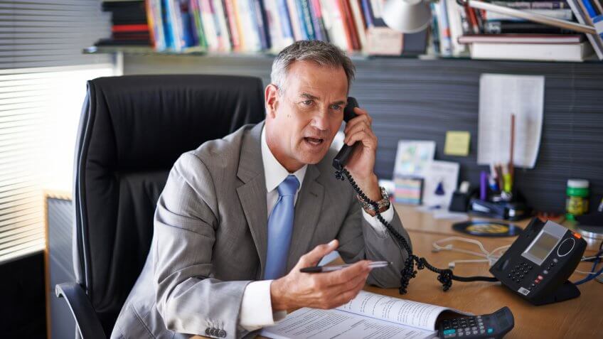 Shot of a mature businessman looking displeased while talking on the phone in his officehttp://195.