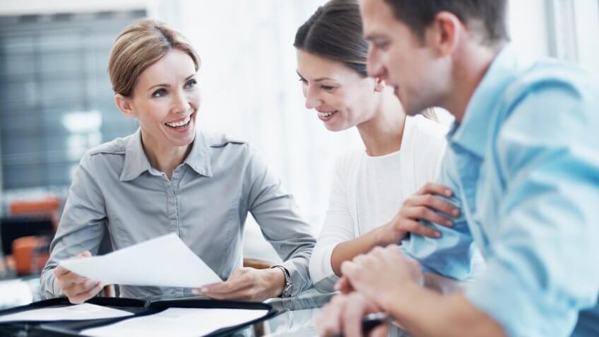 Shot of a consultant explaining a document to a young couple.