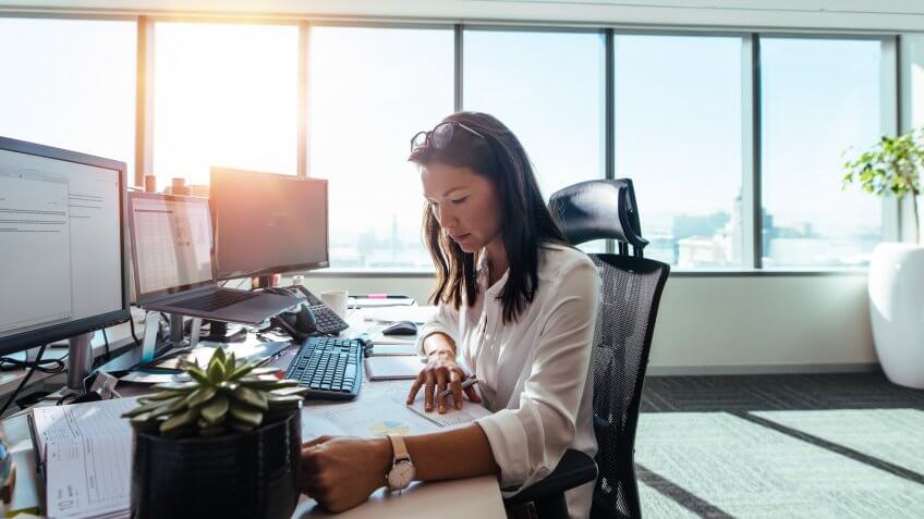 Businesswoman studying business papers on her desk.