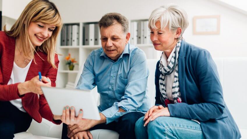 Senior Couple Meeting with Financial Advisor, selective focus to senior man and mature woman listening to financial advisor.